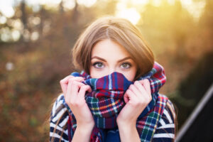Girl experiencing fall allergy issues peeking over scarf at camera