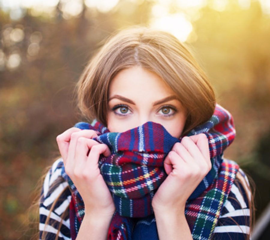 Girl experiencing fall allergy issues peeking over scarf at camera